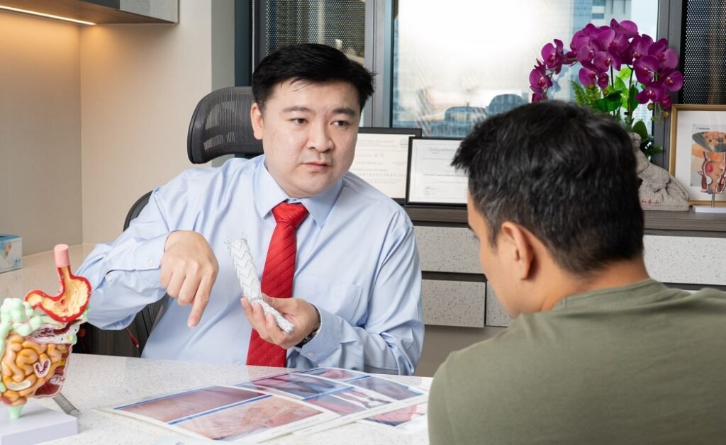 Dr Tay Jia Sheng consulting with a patient, explaining a vascular stent at Spectrum Vascular and General Surgery