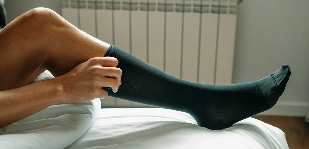 Male runner wearing compression socks while running on a street.