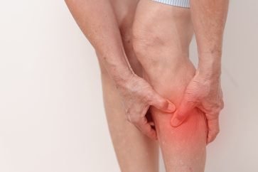 Elderly person holding calf due to vascular leg cramp or poor circulation